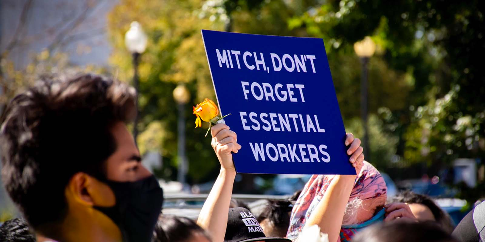 A photo of a man holding a sign in support of essential workers.